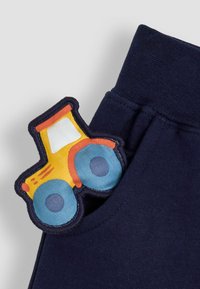 Navyblaue Hosen verfügen über einen strukturierten Patch mit einem gelben und blauen Traktordesign in der Tasche. Weicher Stoff, elastischer Bund und saubere Nähte.