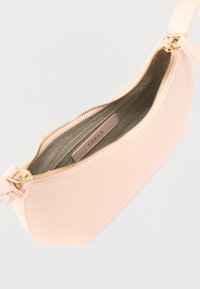 Ροζ δερμάτινο τσαντάκι χειρός με χρυσή φερμουάρ, λεία υφή και επένδυση στο εσωτερικό. Το όνομα της μάρκας εμφανίζεται στην εσωτερική ετικέτα.