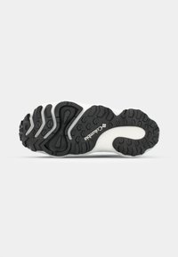 Semelle extérieure en caoutchouc noir avec des motifs de traction texturés, semelle intermédiaire blanche et marquage Columbia. Design courbé pour une meilleure traction.