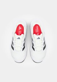 Bijele atletske tenisice s gornjim dijelom od mrežice, crnim akcentima i bijelim vezicama. Crveni ulošci sadrže tekst i logo "ADIDAS TRAINING".