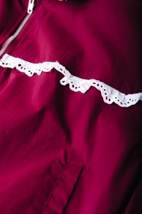 Μπορντό μπουφάν με υφή, με λευκή δαντέλα κατά μήκος του στήθους. Φερμουάρ μπροστά και ορατή πλαϊνή τσέπη.