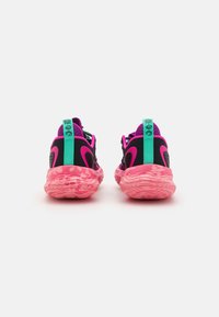 Sorte og pink atletiske sko med en tekstureret pink sål, grøn hælflap og mesh-detaljer. Har unikke mønstre på ydersålen.