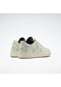 Bílé tenisky s embosovanými texturovanými vzory, kontrastní modrou a žlutou podšívkou a béžovou gumovou podrážkou. Logo Reebok na patě.