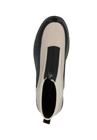 Botín sin cordones con parte superior de cuero beige y panel elástico negro. Presenta un cierre de cremallera, puntera redondeada y suela de goma texturizada.