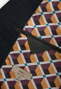 Navy stoffen buitenkant met een geometrisch patroon gevoerd in geel, paars en turquoise. Label toont "NEXT REGULAR FIT 40R."