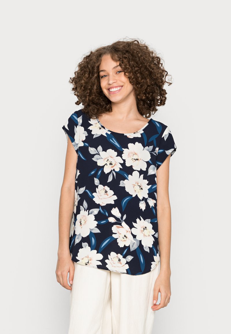 Blusa de manga curta floral em azul marinho com flores brancas e bege. Decote redondo, tecido suave e um corte relaxado com a bainha arredondada.