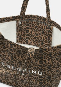 Torba na ramię w panterkę w brązowo-czarnym kolorze z białym logo, przestronna wnętrze oraz zamek błyskawiczny na górze. Posiada dwa solidne uchwyty.