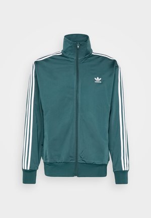 Mørkegrøn Adidas lynlåstrøje med hvide tre striber på ærmerne og trekløver-logo på brystet, høj krave, ribkant ved ærmer og bund.