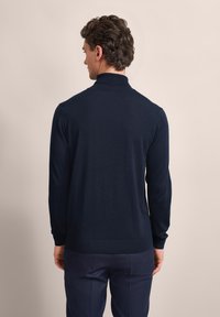Dunkelblauer Pullover mit hohem Kragen und langen Ärmeln, aus weichem Material. Verfügt über gerippte Bündchen und einen Saum, minimalistisches Design.