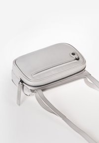 Borsa a tracolla in pelle grigia con forma rettangolare, chiusura con zip e tasca frontale. Presenta tracolle sottili e una superficie liscia.