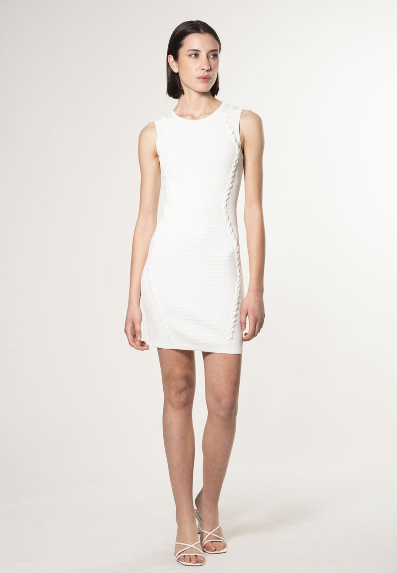 Robe blanche sans manches avec des rayures horizontales texturées et un contraste de bord le long des côtés. Silhouette ajustée avec un ourlet droit.