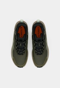 Grüne und schwarze Sportschuhe aus strukturiertem Mesh und synthetischen Materialien, mit gepolsterter Sohle und kontrastierenden orangefarbenen Einlegesohlen.