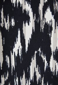 Textiel met een zwart-wit ikatpatroon, voorzien van strepen en een zachte textuur, die een mix van krachtige contrasten en subtiele variaties toont.