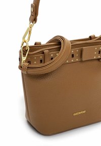 Pruun nahast käekott tekstuurse viimistlusega, lame rihmaga, millel on kuldsed aksendid, ja turvaliseks kinnitamiseks klamber. Logo on näha koti küljel.