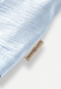 Tessuto azzurro chiaro con un pattern testurizzato, caratterizzato da un'etichetta beige visibile con "Henri Lloyd" in marrone. Texture morbida e liscia.