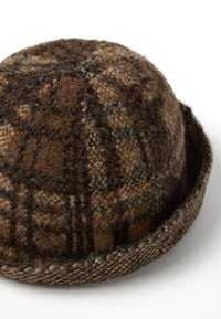 Cappello di lana marrone con motivo a quadri. Forma tondeggiante con finitura testurizzata e visiera piatta. Accenti di tonalità marrone scuro e beige.