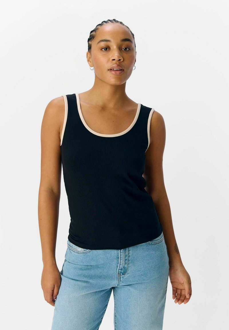 Schwarzes, geripptes Tanktop mit runder Ausschnitt und cremefarbener Paspelierung. Tragen Sie es mit hellblauen Jeans, die eine glatte Textur und eine taillierte Passform haben.