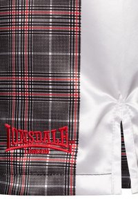 Kárované šortky s čiernymi, bielymi a červenými vzormi, s vyšitým červeným logom "Lonsdale London" na prednej strane a so štrbinkovými detailmi po stranách.