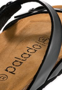 Sandalo nero con una fascia in pelle liscia e una soletta in camoscio marrone. Presenta il nome del marchio impresso e un design del plantare sagomato.