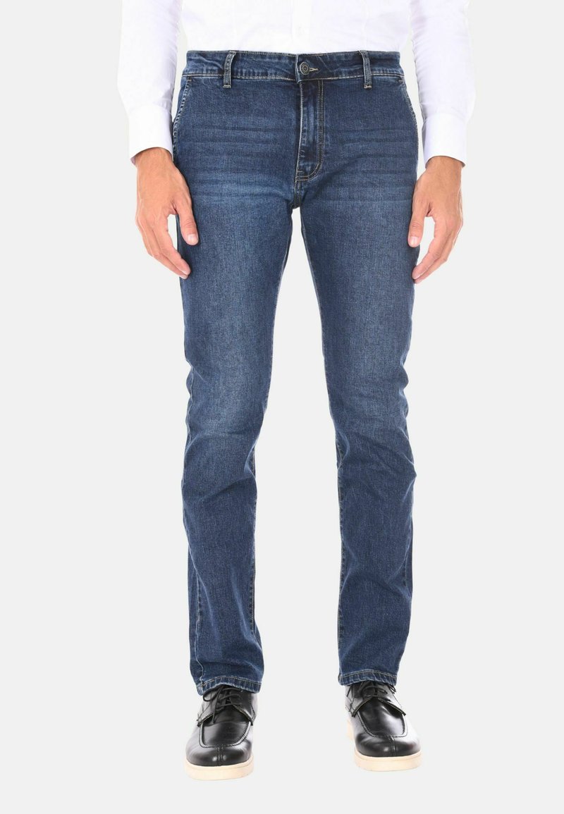 Jeans in denim blu scuro con un taglio dritto classico, design a cinque tasche e una trama sottile. Abbinati a scarpe nere e una camicia bianca.