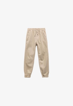 Helle beige Jogginghose aus Baumwolle mit elastischem Bund, Kordelzug, seitlichen Taschen und schmal zulaufenden Bündchen an den Knöcheln.