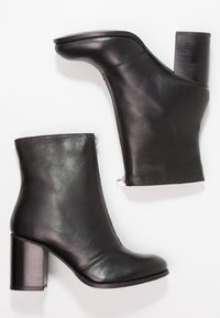 Černé kožené kotníkové boty s kulatou špičkou, bočním zipem a masivním blokovým podpatkem. Povrch je hladký s jemným leskem.