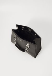 Sac à main en cuir noir avec quincaillerie argentée. Forme structurée, dotée d'une ouverture supérieure et d'une poche intérieure. Doublé, avec un détail logo à l'avant.