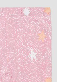 Roze legging met een textuurpatroon van witte stippen en zeesterpatronen in oranje en wit. Elastische tailleband met schelpe-accent.