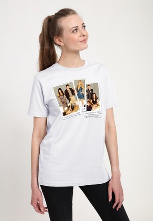 Ung kvinde med lang hestehale iført en hvid T-shirt med billeder af skuespillere og tekst fra tv-serien Gossip Girl.