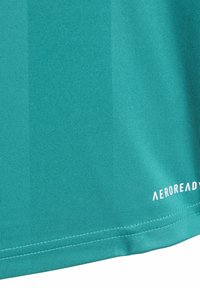 Tealowa tkanina z widocznym przeszyciem i białym napisem "AEROREADY" wydrukowanym blisko dolnej krawędzi po prawej stronie.