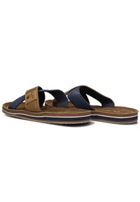 Brown and navy flip-flops with cross straps, soft cushioning, textured footbed, and a white-striped side detail. Lightweight design.