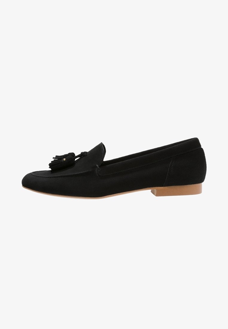 Mocassin en suède noir avec détail pompon sur le dessus et talon plat marron clair, vue latérale sur fond blanc.