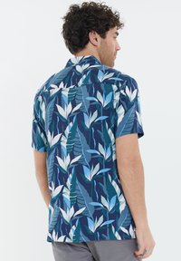 Korte mouwen shirt met een marineblauwe achtergrond en een gedurfde bloemenprint in wit, lichtblauw en groen. Gladde stof met een relaxte pasvorm.