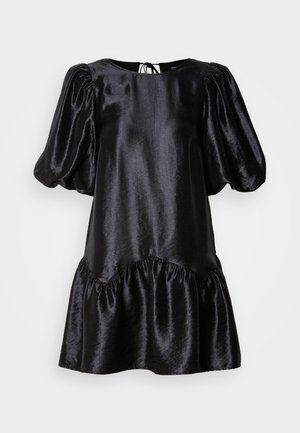 Must musträtik, millel on puhvärvargad, ümar kaelus ja rufflesäär. Omab seljasaumast reguleeritavat sidumist ja sujuvat tekstuuri.