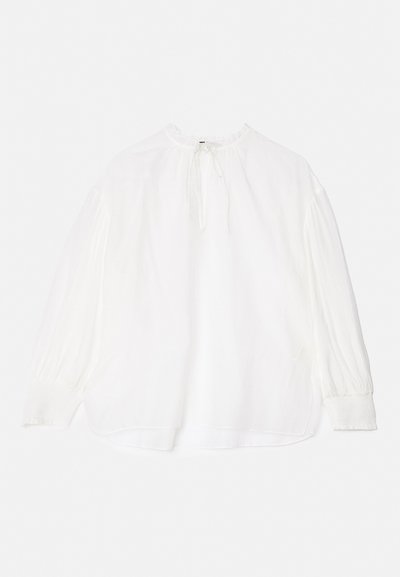 Blouse blanche avec des manches longues et froncées, un col noué et une coupe décontractée. Présente un tissu légèrement texturé et des poignets élastiques.
