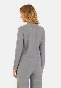 Maglione grigio a maglia con righe testurizzate, design aderente, scollatura rotonda e maniche lunghe, visto da dietro.