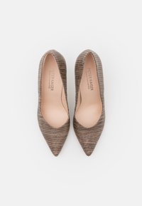 Zapatos de tacón de punta afilada con un patrón de cocodrilo marrón texturizado, con un vampiro bajo y un interior suave. Nombre de la marca grabado en el interior.