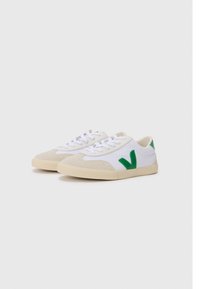 Sneakers med en beige semsket tåhette, hvit kanvas kropp og grønne gummidetaljer, med flate lisser og en teksturert beige såle.