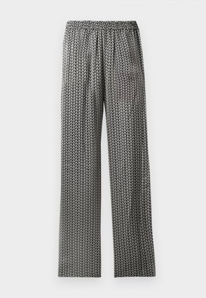 Pantaloni ampi a righe bianche e nere con vita elastica. Il design presenta un motivo geometrico ricorrente a forma di freccia.
