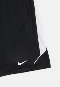 Pantalones cortos deportivos negros con paneles laterales blancos y un pequeño swoosh blanco de Nike cerca del dobladillo inferior en la pierna izquierda.