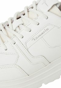 Vita sneakers i slät läder med meshdetaljer. Har snörning, logotyp och en texturerad gummisula. Ren och minimalistisk design.