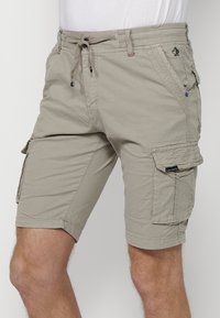Beige Cargo-Shorts aus leichtem Material, mit seitlichen Taschen, einem elastischen Bund und einem Kordelzug zur Anpassung.