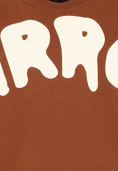 Tkanina w kolorze rdzy z dużymi białymi stylizowanymi literami, zawierającymi małe wycięcia przypominające oczy.