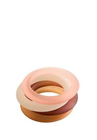 Anelli in silicone impilati in diverse sfumature di pesca, beige e marrone; texture liscia con bordi arrotondati e una forma circolare uniforme.
