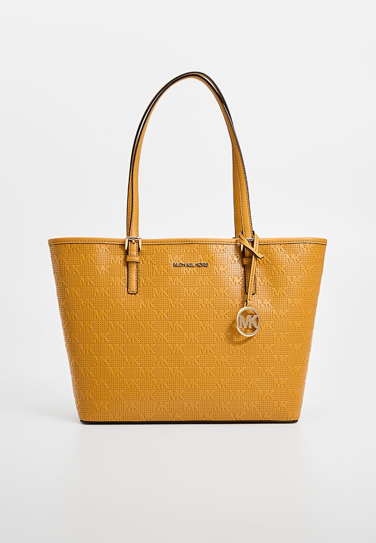 Gelbe Kunstleder-Tote-Tasche mit geprägtem Muster, schwarzem Rand, doppelten Griffen und einem hängenden silbernen Logo-Anhänger. Misst ungefähr 30 cm in der Höhe.