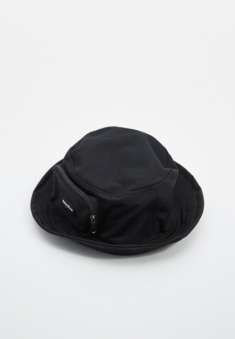 Chapeau de seau noir en tissu texturé, muni d'une poche zippée sur le côté et d'un bord incurvé. Comprend un patch logo cousu.