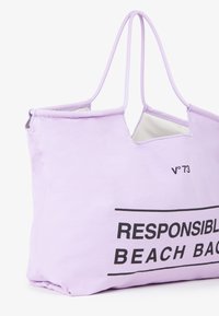 Borsa a mano in tessuto lavanda con due manici, caratterizzata da un grande testo stampato "BAGAGLIO DA SPIAGGIA RESPONSABILE" in nero bold. Texture liscia e apertura superiore.