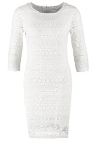 Robe blanche jusqu'aux genoux avec manches trois-quarts, présentant des motifs floraux en dentelle délicate et un col rond avec une fermeture éclair au dos.