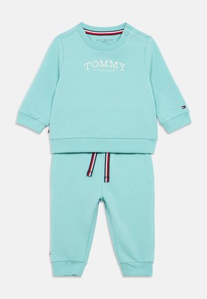 Completo per bambino con felpa azzurro chiaro e pantaloni con logo "Tommy Hilfiger" sul petto e coulisse a righe sui pantaloni.