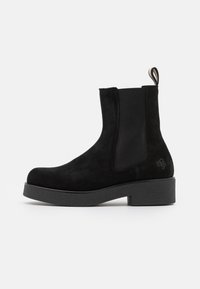 Černé semišové kotníkové boty s elastickými bočními panely, plochou gumovou podrážkou a zadním poutkem. Mají kulatou špičku a minimalistický design.